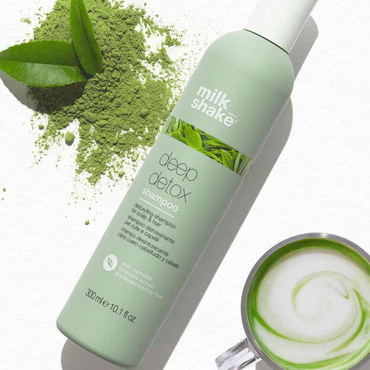 Bottiglia verde su tavolo bianco. Piccola tazza con un infuso alla erbe all'interno sulla parte basse dell'immagine.